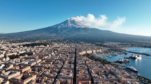 Mount Etna smoking above Catania city and harbor, Sicily