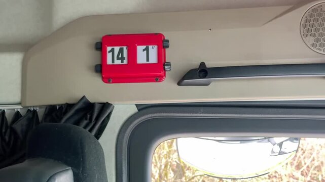 Interior close up of a red height indicator sign in a truck cabin above the window and safety mirror