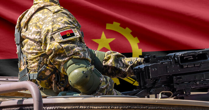 Angola flag with soldier at machine gun turret in front of it. Closeup side view.