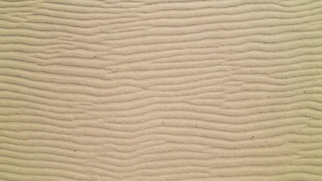 Close-up view of rippled sand texture, abstract pattern created by wind and water.