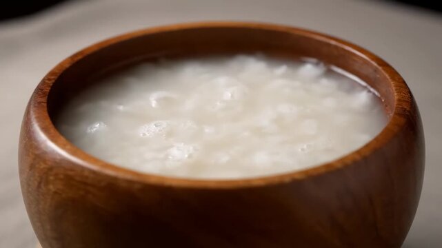 Close-up of hot rice porridge (congee) served in a traditional wooden bowl. Healthy Asian comfort food and breakfast staple.