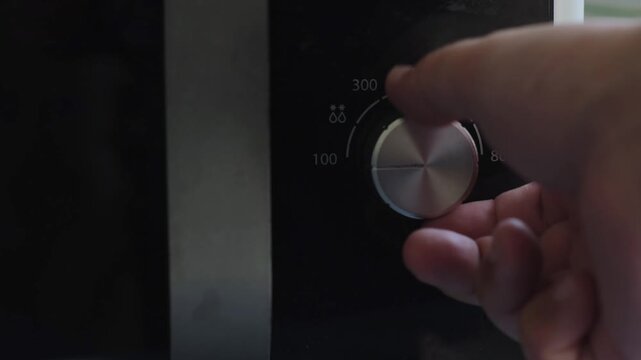 Hand turning a microwave power dial creating multiple mechanical clicking sounds