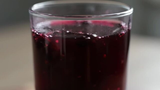 Extreme Close-Up of Dark Red Berry Juice or Homemade Compote Served in a Glass Tumbler