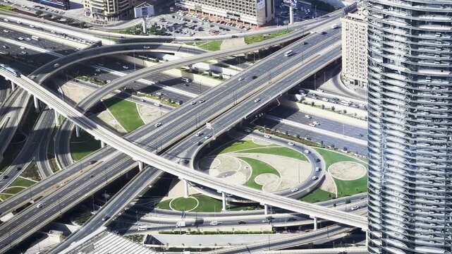Spectacular and breathtaking upper view on modern multi-level traffic interchange with driving cars and flowerbeds on ground in Dubai.