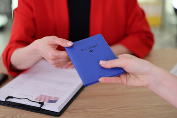 At a vibrant airport check-in desk, a traveler excitedly hands their blue passport to a friendly staff member. Paperwork surrounds them, symbolizing the beginning of a new adventure.