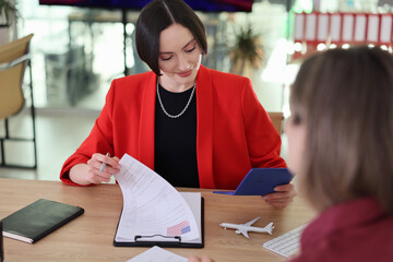In a bright, stylish office, two women engage in an important meeting, discussing travel plans and reviewing documents. The atmosphere is professional and focused on collaboration.