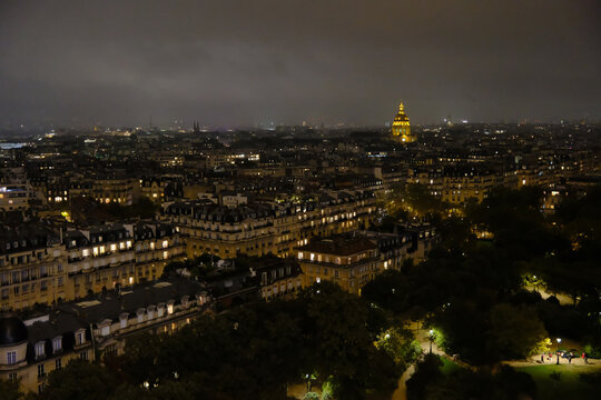 High-angle night view of Paris cityscape featuring the illuminated golden dome of Les Invalides