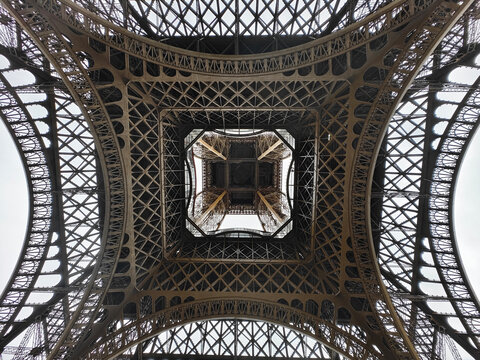 Symmetrical low angle shot of the intricate iron structure under the Eiffel Tower