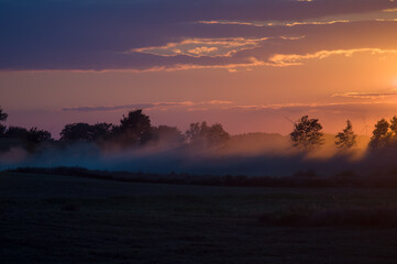 Krajobraz kolorowy zachód słońca mgła nad polami. © Monika