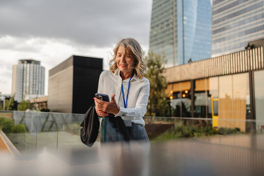 Businesswoman using smartphone outdoors in urban city setting