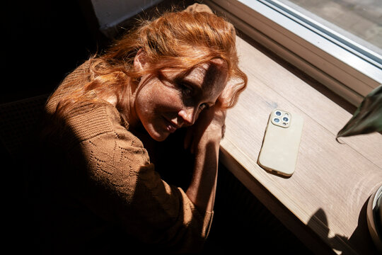 Person relaxing at cafe during digital detox in sunlight by window