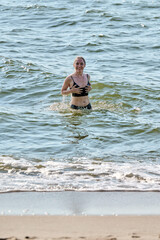 Fototapeta premium Young woman swimming in Baltic Sea near sandy shore on sunny day