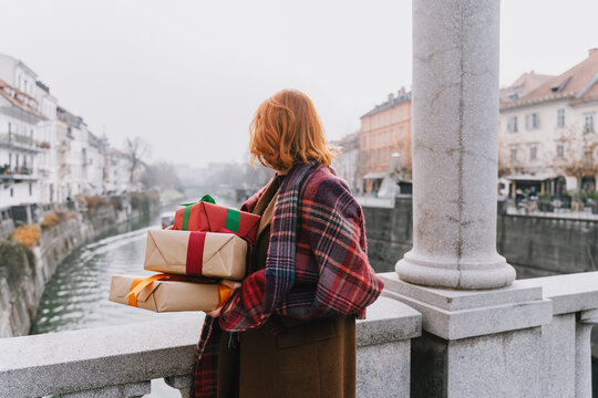 Woman holding gifts outdoors in city showing optimism and sharing