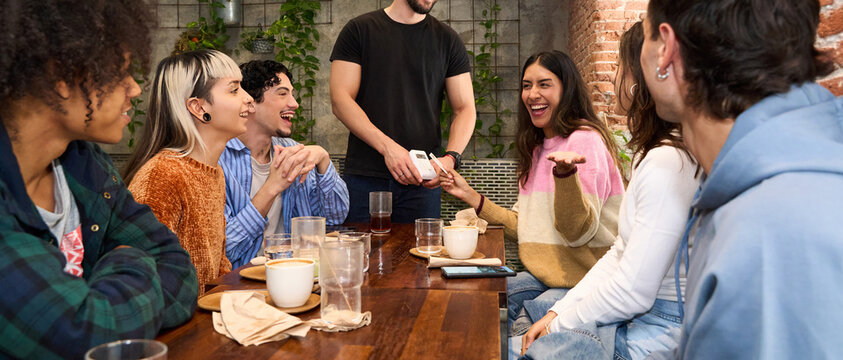 Group of friends laughing and sharing drinks at a cozy cafe