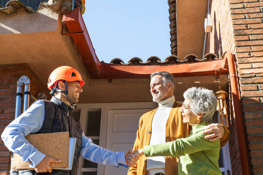 Engineer greeting homeowners for solar panel installation at house entrance