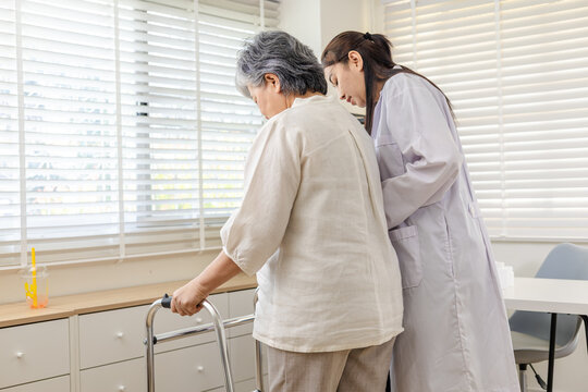 Senior mobility rehabilitation, healthcare doctor professional helps patient practice steps with walker, balance control, fall prevention guidance, monitoring results, follow up for independence