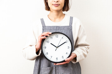 白背景に時計を持つ主婦