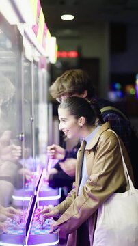 Friends enjoy a fun night out at a vibrant arcade, laughing and playing a claw machine game. Their joyful expressions capture the excitement and camaraderie of urban entertainment.