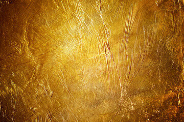 Luxury golden foil texture background with shiny metallic surface reflecting light and sophisticated crumpled effect for premium holiday or jewelry design