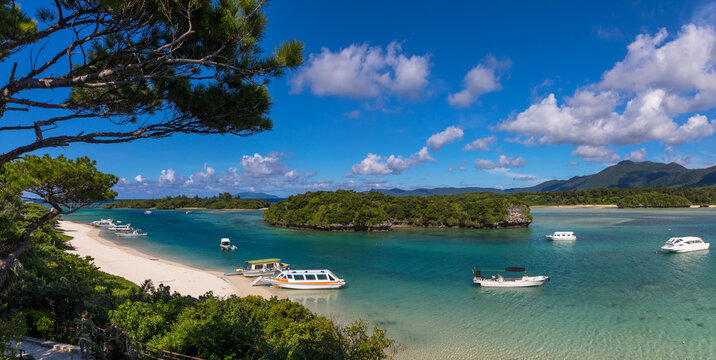 Glass bottom boats in the tropical lagoon beach with clear blue water and white sand in Kabira bay, Yaeyama Islands, Ishigaki, Japan