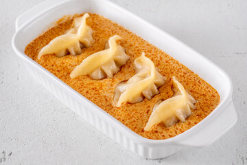 Gyoza dumplings served in creamy Tom Yum sauce with elegant minimalist presentation