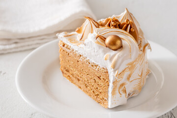 Slice of Medovik honey cake with toasted meringue and golden garnish