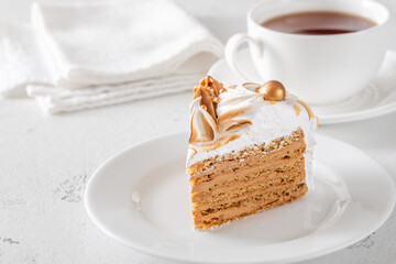 Slice of Medovik honey cake with toasted meringue and golden garnish