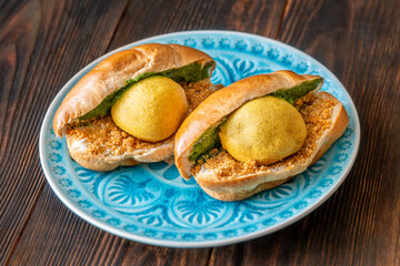 Authentic Vada Pav Indian street food with spicy chutney on rustic wooden background