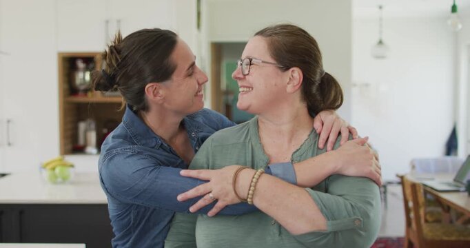 Portrait of caucasian lesbian couple looking at camera, embracing