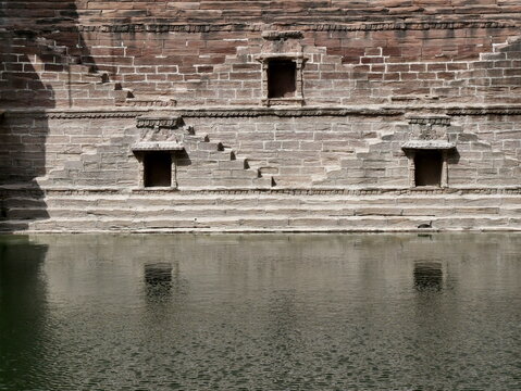 Toorji Ka Jhalra Bavdi stepwell in Jodhpur, India with steeps going to the water reservoir. symmetry reflected in water
