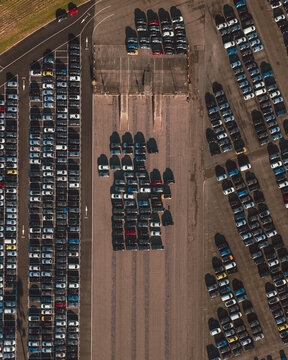 Aerial view of tightly packed rows of cars parked in an orderly fashion, casting long shadows under the midday sun, Cite des Pains, Nouvelle-Aquitaine, France.