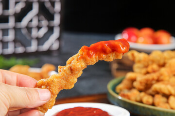 Enjoying Crispy Fried Pork Strip with Spicy Red Sauce - Delicious Comfort Food Snack Time