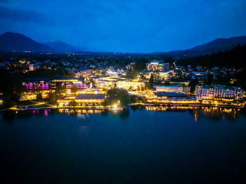 Aerial view of the illuminated town reflecting on the still lake waters under the twilight sky, Bled, Radovljica, Slovenia.