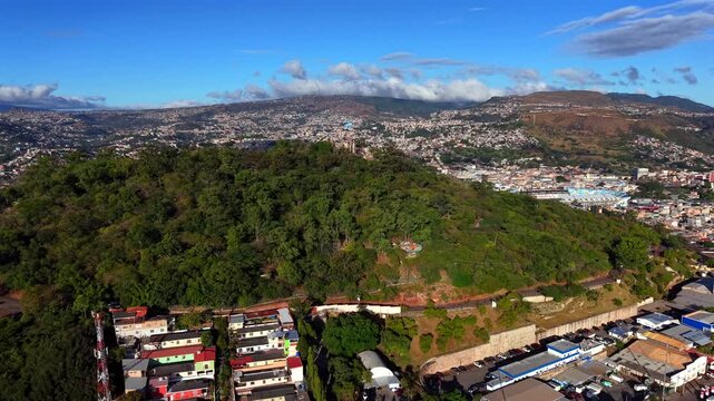 Beautiful aerial view of Tegucigalpa, capital of Honduras, with Juana hill and the Honduran flag waving, surrounded by mountains and urban valley