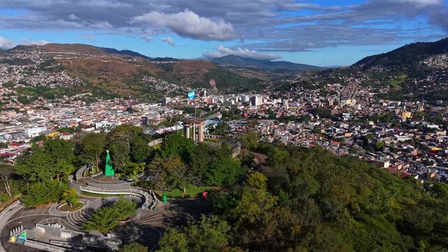 Tegucigalpa Honduras - 01 26 2026: Beautiful aerial view of Tegucigalpa, capital of Honduras, with Juana hill and the Honduran flag waving, surrounded by mountains and urban valley