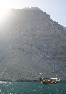 Dhow sailing in the fjords in front of mountains, Musandam, Khasab, Oman