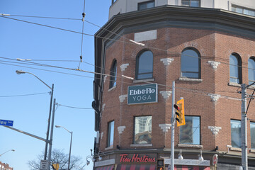 Naklejka premium exterior building facade and signs for Ebb & Flo Studio and Tim Hortons coffee shop southeast corner of Danforth Av and Broadview Av, Toronto