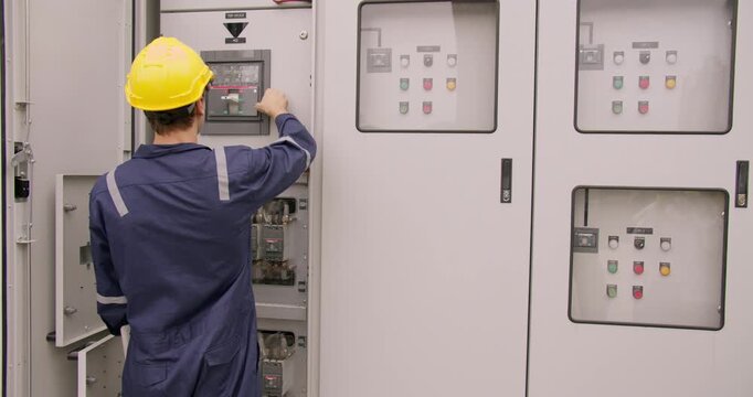 Focused engineer in a hard hat precisely operates an outdoor electrical control panel. This highlights critical power system management and diligent industrial maintenance, conveying safety,