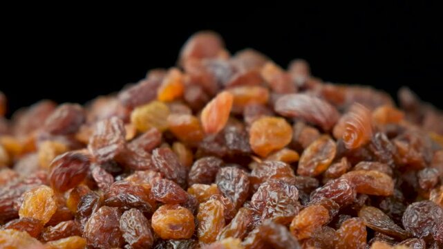 Brown raisins poured slow motion, macro food background