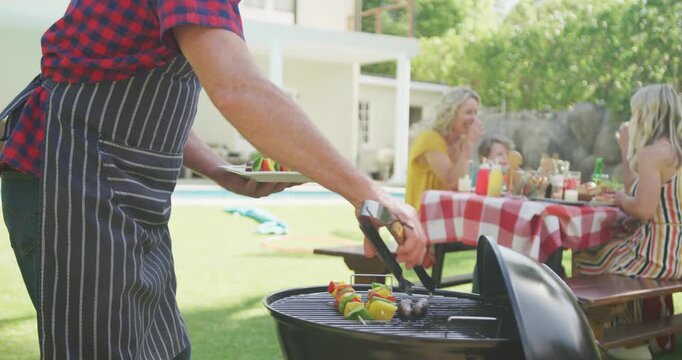 Happy caucasian family having barbecue and eating in garden