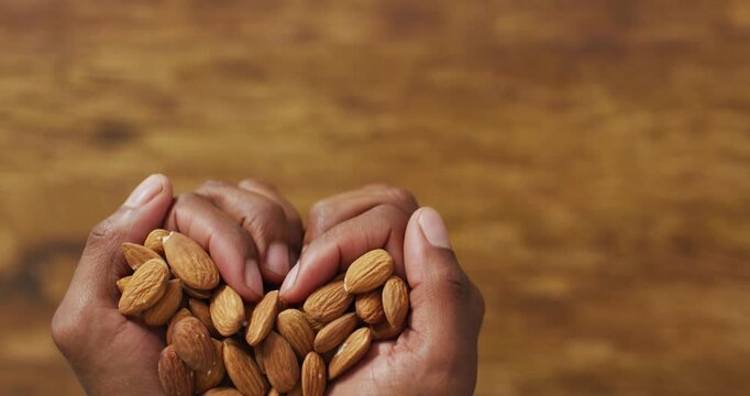 Video of almonds in the hands on wooden background