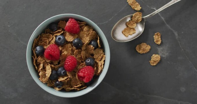 Video of cereals and fruit in ceramic bowl on stone kitchen worktop