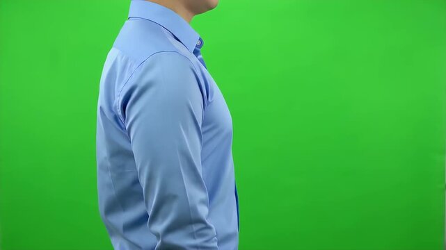 Man standing sideways wearing a light blue shirt in front of a green background video footage