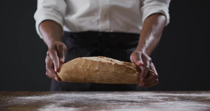 Video of cook holding loaf of bread on black background