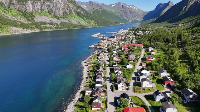 14 july 2025, Gryllefjord, Norway. Aerial, forward drone flight above village, during summer. Mountains left en right side and in background. Streets and houses, small town on Senja island.