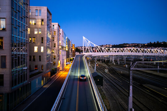 night urban bridge near Oslo Norway with railway road traffic and strong illumination framing architecture lines and fast city transport