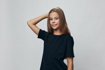 Girl, child, and portrait with confident pose in black t shirt on gray background. Teenager standing with hand behind head and slight smile for child fashion or lifestyle.
