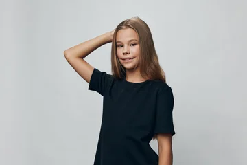 Fotobehang Onderzeeër Girl, child, and portrait with confident pose in black t shirt on gray background. Teenager standing with hand behind head and slight smile for child fashion or lifestyle.  © SHOTPRIME STUDIO