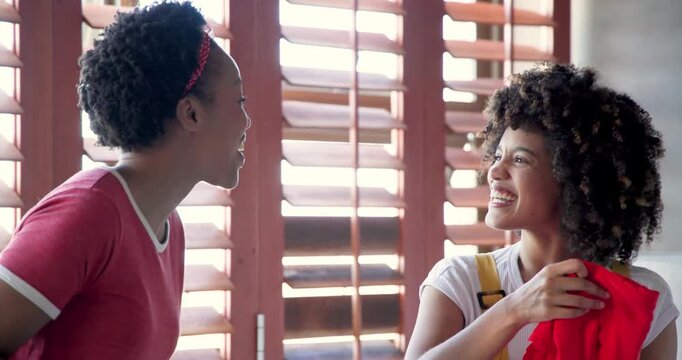 Sharing colorful fabric, African American women embracing happiness together at home