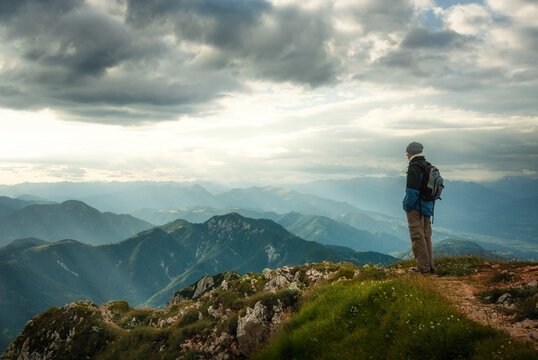 Hiker enjoying the majestic and moody view on a mountain top. The Austrian and Slovenian Alps with dramatic clouds.